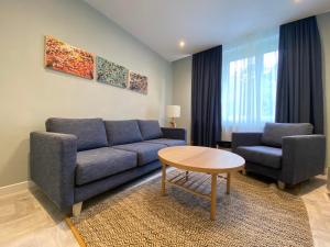 a living room with a blue couch and two chairs at Apartman Teatar in Sombor
