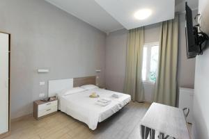 1 dormitorio con 1 cama blanca y TV en Residence Conchiglie, en Marina Romea
