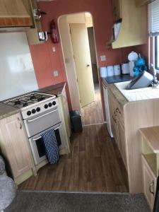 a small kitchen with a stove and a sink at A4 THE CHASE 6 Berth Pet Friendly Caravan With Decking in Ingoldmells