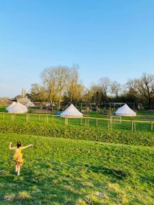 a woman is standing in a field with a kite at Willow Grove Farm Glamping in Lakenheath +12 photos