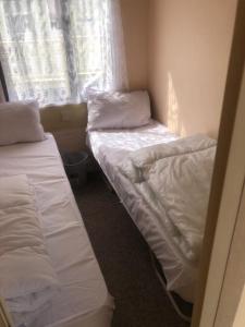 two beds in a small room with a window at A4 THE CHASE 6 Berth Pet Friendly Caravan With Decking in Ingoldmells