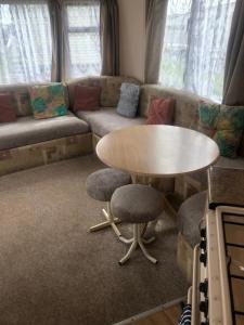 a living room with a table and a couch at A4 THE CHASE 6 Berth Pet Friendly Caravan With Decking in Ingoldmells