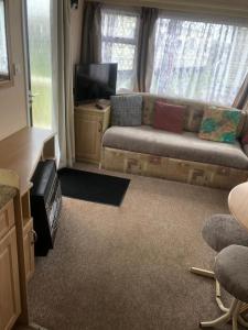 a living room with a couch and a flat screen tv at A4 THE CHASE 6 Berth Pet Friendly Caravan With Decking in Ingoldmells