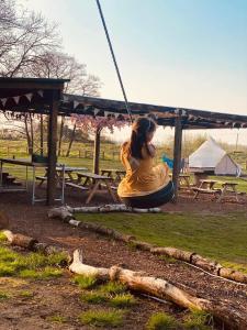 Una chica sentada en un columpio en un parque en Willow Grove Farm Glamping, en Lakenheath