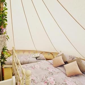 a room with a bed and pillows in a tent at Willow Grove Farm Glamping in Lakenheath