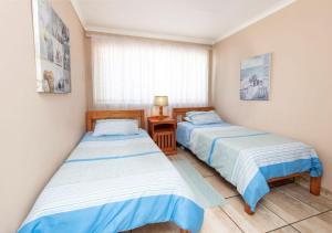 a bedroom with two beds and a table and a window at 82 De Bakke Terrace in Mossel Bay