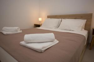 un grand lit avec deux serviettes blanches dessus dans l'établissement George‘s Place Kastrosikia, à Kastrosikia