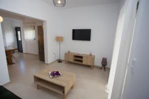 un salon avec une table et une télévision au mur dans l'établissement George‘s Place Kastrosikia, à Kastrosikia
