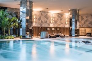 a swimming pool in a hotel lobby with chairs at Grand Hyatt Barcelona in Barcelona