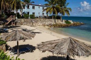 a beach with umbrellas and chairs and the ocean at Northshore Seaside Suites in Saint Johnʼs