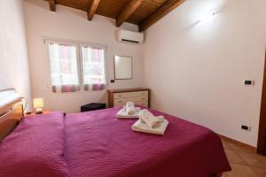a bedroom with a purple bed with towels on it at GaLi eco-apartment in Olbia