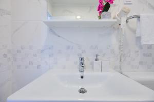 a white bathroom with a sink with a faucet at Apartment Manilu in Dubrovnik