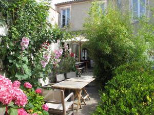 - un jardin avec une table en bois et quelques fleurs dans l'établissement Hôtel Le Sénéchal, à Ars-en-Ré