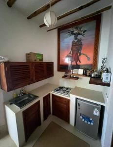 uma pequena cozinha com um lavatório e uma pintura na parede em Miky House em Watamu