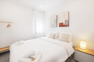 - une chambre blanche avec un grand lit blanc et une lampe dans l'établissement Vento Do Mar Apartment by Olala Homes, à Cascais