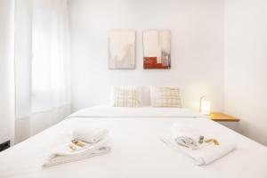 a white bedroom with a white bed with two towels at Vento Do Mar Apartment by Olala Homes in Cascais