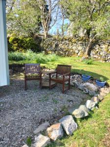 two wooden benches sitting next to a stone wall at Lavender hut in Brackloch