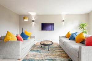a living room with two couches with colorful pillows at The Argyle Apartment - Luxury - Parking in St Andrews