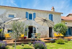 een huis met een patio met stoelen en een parasol bij Le Petit Caviste - Chambres D'hôtes & Suites in Castagnol