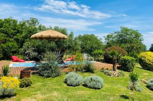 een tuin met een tafel en een parasol bij Le Petit Caviste - Chambres D'hôtes & Suites in Castagnol