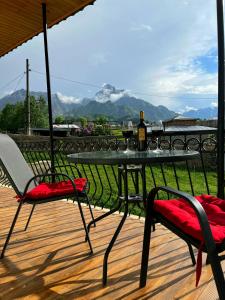 een tafel met twee stoelen en een fles wijn op een terras bij Hotel Garbani in Kazbegi