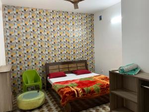 a bedroom with a bed and a green chair at IMBUE STAYS in Dehradun