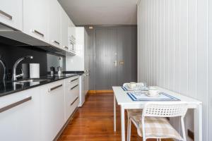 a kitchen with white cabinets and a white table and chairs at Ayala apartment by People Rentals in Bilbao