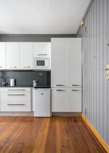 a kitchen with white cabinets and a wooden floor at Ayala apartment by People Rentals in Bilbao