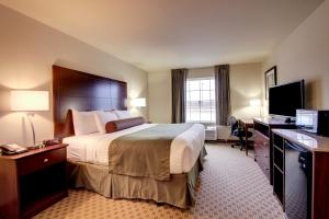 a hotel room with a large bed and a desk at Cobblestone Inn & Suites - Linton in Linton