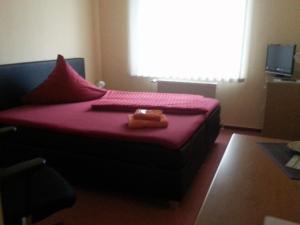 - une chambre avec un lit doté de draps rouges et une fenêtre dans l'établissement Zur Linde, à Ostrau