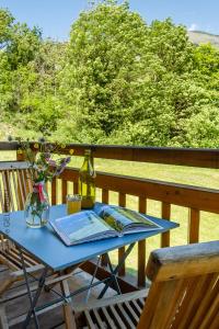 un tavolo con una bottiglia di vino e un libro su una terrazza di Chalet aux 3 biches a Mieussy