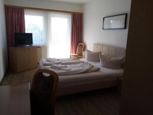 1 dormitorio con 1 cama con silla y ventana en Zur Linde, en Ostrau