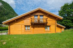 a log cabin with a balcony in a field at Chalet aux 3 biches in Mieussy