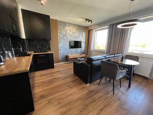 a kitchen and living room with a couch and a table at Tricity Apartments - Wilga Park in Gdańsk