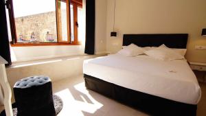 um quarto com uma grande cama branca e uma janela em El silencio boutique room em Segóvia