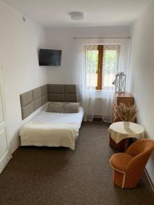 a bedroom with a bed and a chair and a window at Pensjonat Na Kolumba in Kołobrzeg