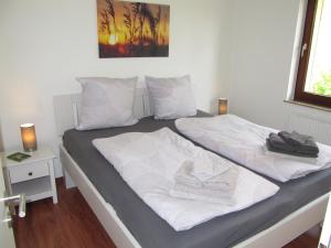 - un lit avec des draps blancs et des serviettes dans l'établissement Ferienwohnung "Am Kurpark", à Sankt-Andreasberg