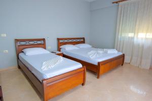 two twin beds in a room with a window at White Hotel in Borsh