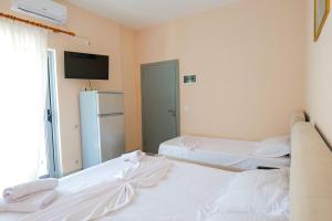 two beds in a room with a tv and a refrigerator at White Hotel in Borsh