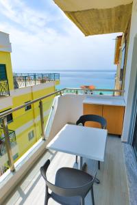 a table and chairs on a balcony with the ocean at White Hotel in Borsh