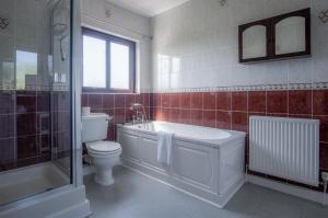 a bathroom with a toilet and a tub and a sink at Avoca - 3 Bedroom Holiday Home - Llangennith in Llangennith +48 photos