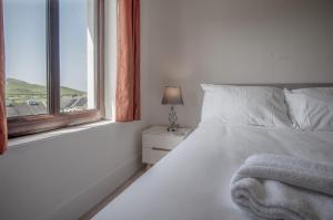 a white bedroom with a bed and a window at Avoca - 3 Bedroom Holiday Home - Llangennith in Llangennith