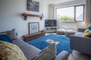 a living room with a couch and a tv at Avoca - 3 Bedroom Holiday Home - Llangennith in Llangennith
