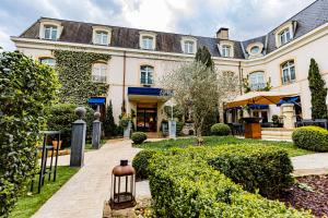 een uitzicht op een gebouw met een tuin bij Hostellerie Cèdre & Spa Beaune in Beaune