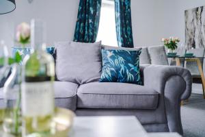 Carterson Serviced Apartment Coventry في كوفينتري: غرفة معيشة مع أريكة رمادية مع وسائد زرقاء