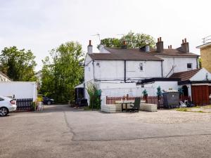 ein weißes Haus mit einem Zaun auf einem Parkplatz in der Unterkunft Old Oak Tree Inn in Hounslow