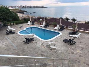 una piscina con tumbonas y sillas junto al océano en Black Sea Paradise Hotel, en Sozopol