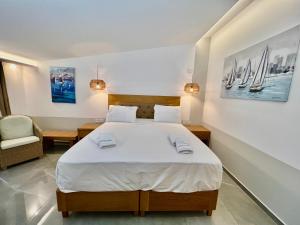 a bedroom with a large bed and a chair at Hotel Pefkohori Beach in Pefkochori