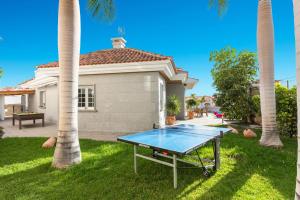 una mesa de ping pong frente a una casa con palmeras en villa leonardo en Puerto de Santiago