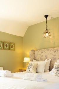 a bedroom with a bed with a chandelier at Casina Cottage in Quenington